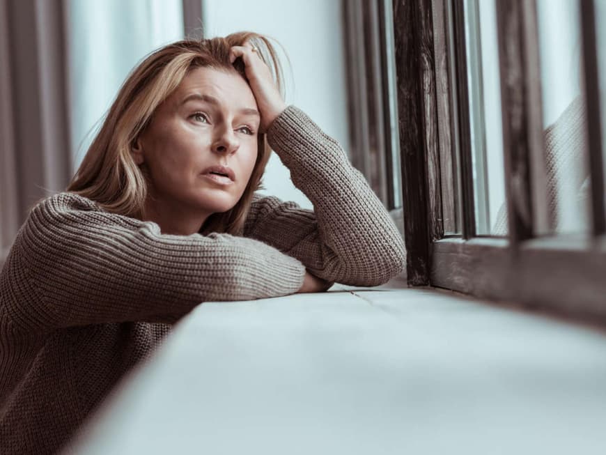 Frau sitzt traurig am Fenster